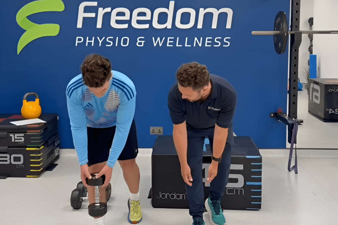 physio guiding patient through single leg deadlift holding dumbbell